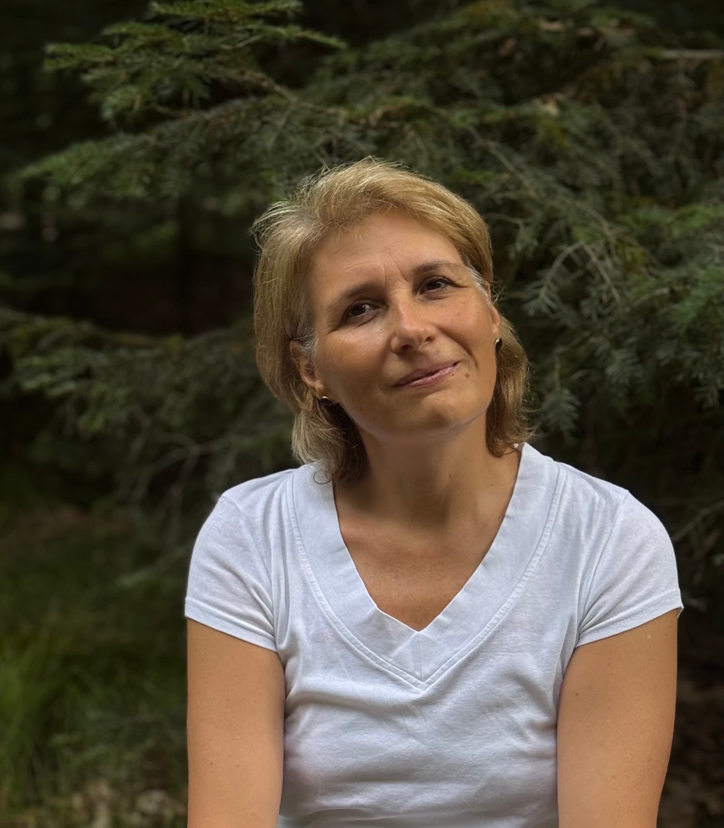 Judit Wolf-Schäffer lächelt vor dunklem Tannengrün in die Kamera